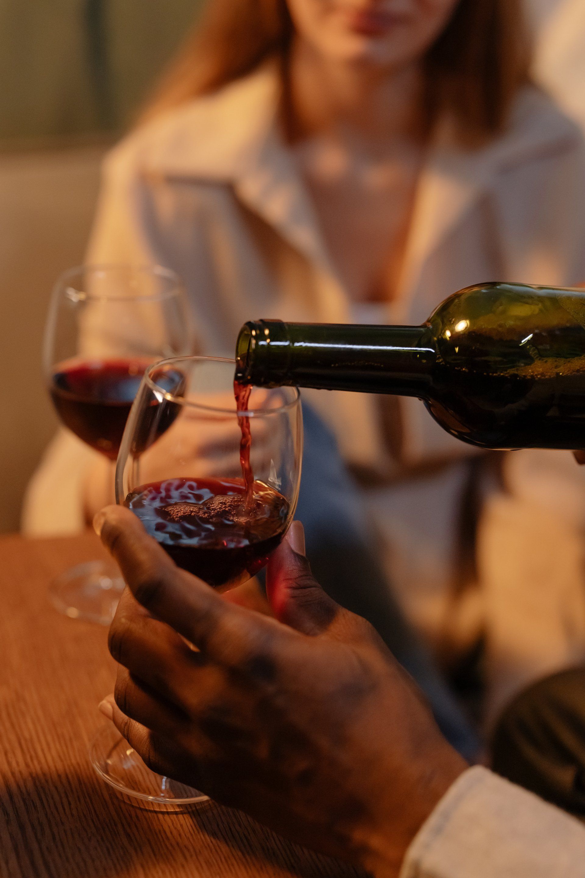 A man is pouring red wine into a glass.