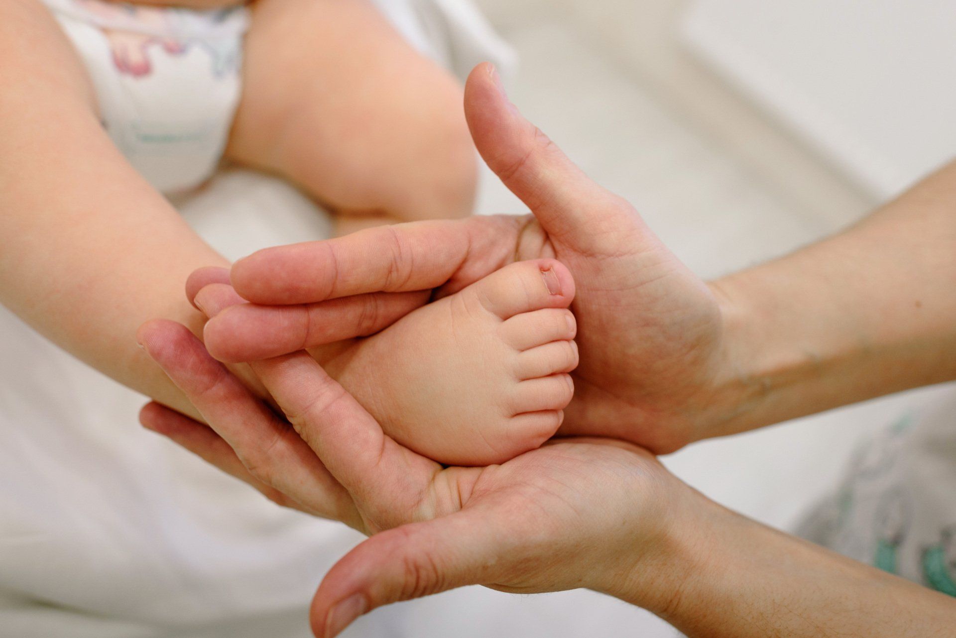 big pair of hands holding a baby's foot