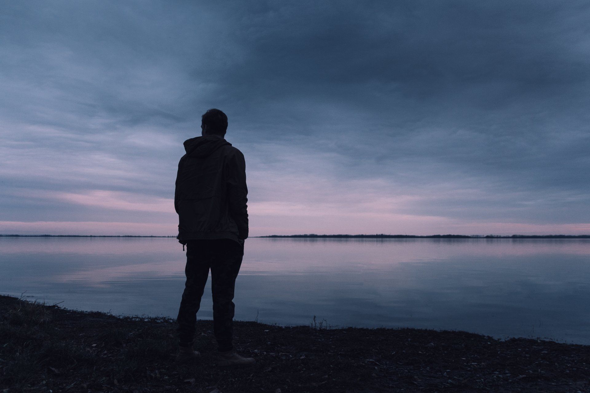 Un uomo solo è in piedi sulla riva di un lago