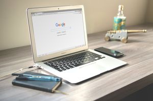 A laptop computer is open to a google page on a wooden desk.