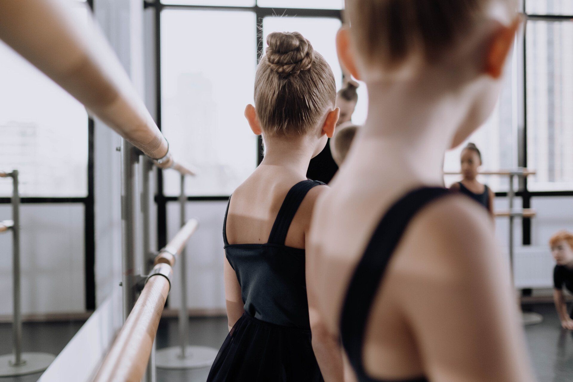 Ballet dancers standing with their backs to the camer in front of a large mirror