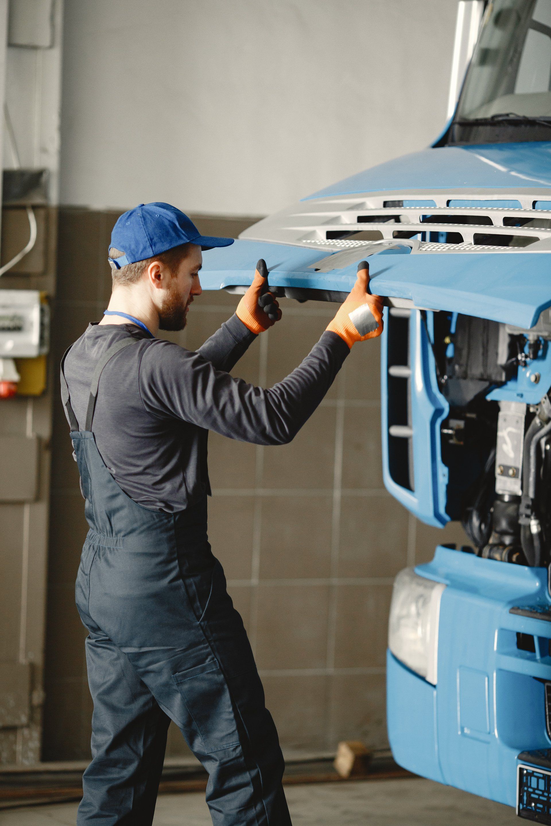 a man is working on a blue truck with the hood up