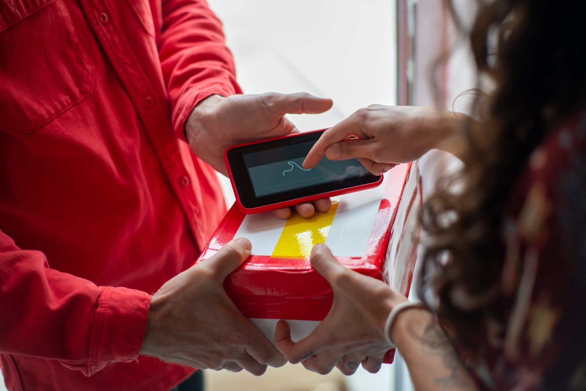 A man is giving a woman a pizza box and a cell phone.