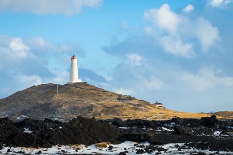 A lighthouse on top of a hill with a blue sky in the background