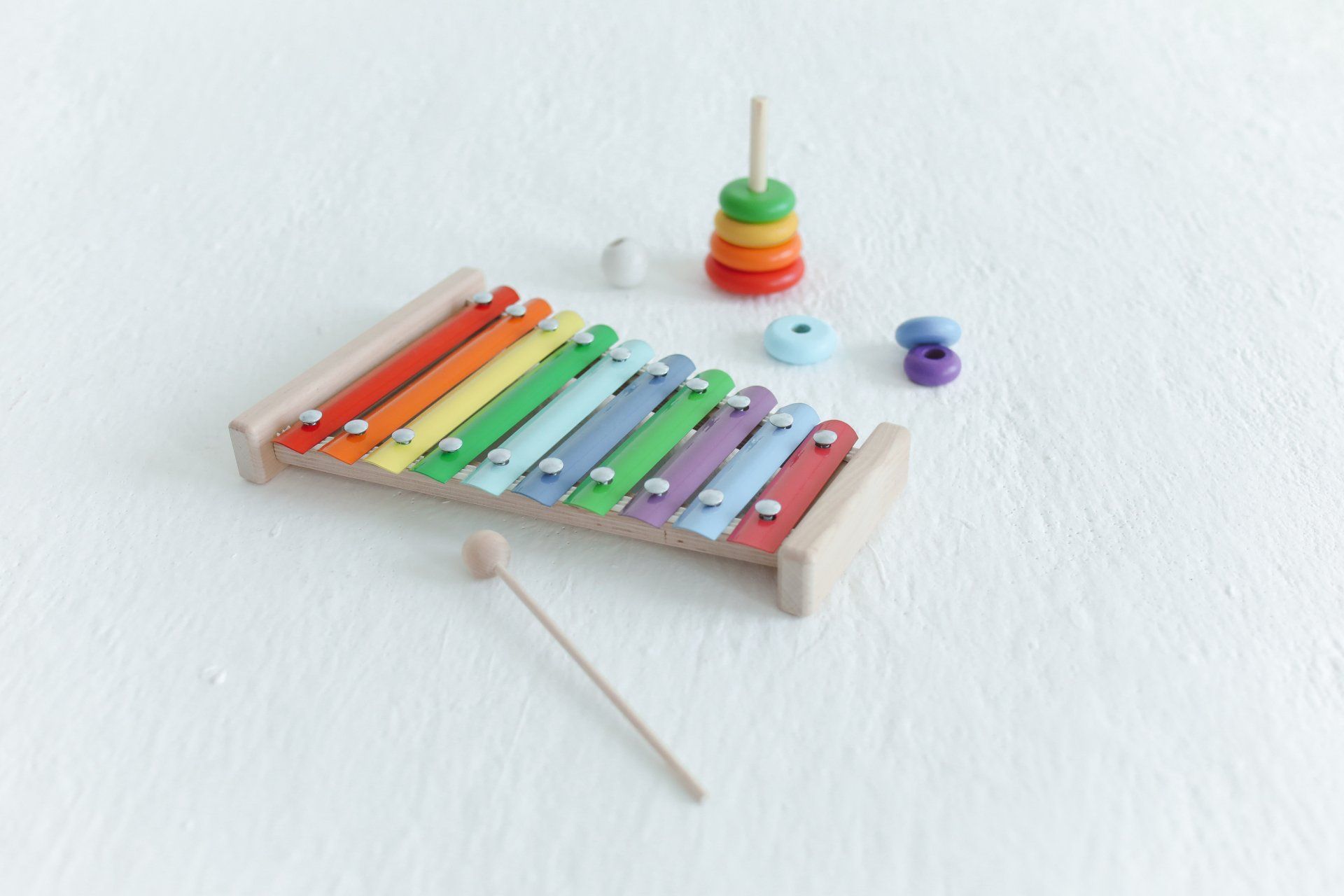 a colorful xylophone is sitting on a white surface next to a stacking toy .