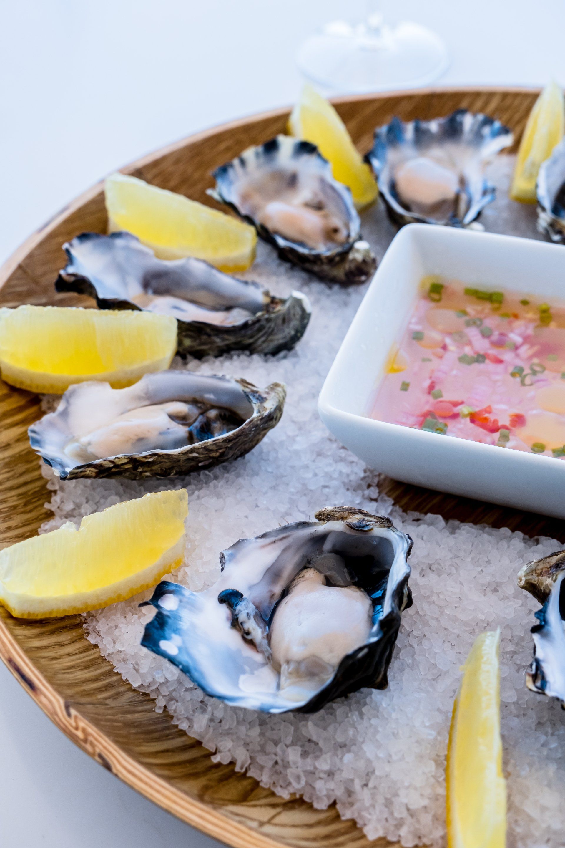A plate of oysters with lemon slices and dipping sauce