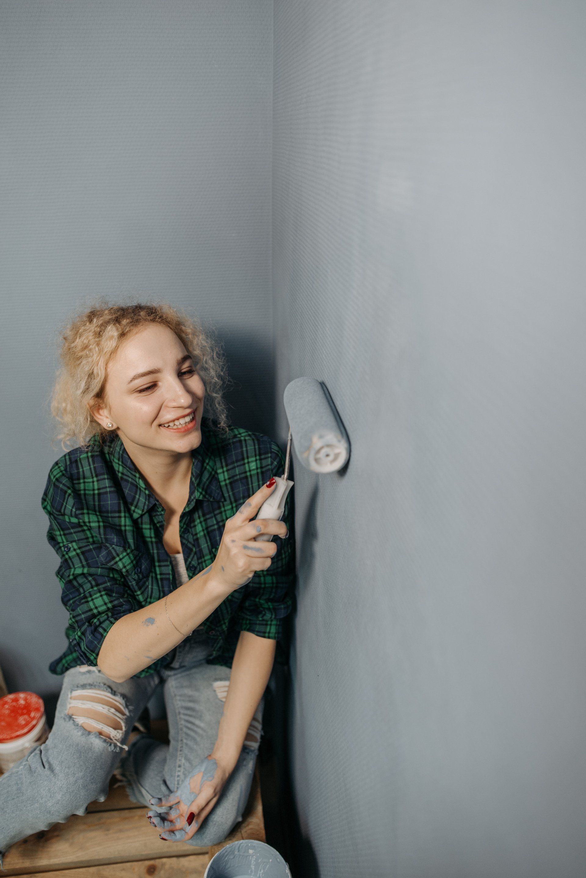 A picture of a woman painting a grey wall