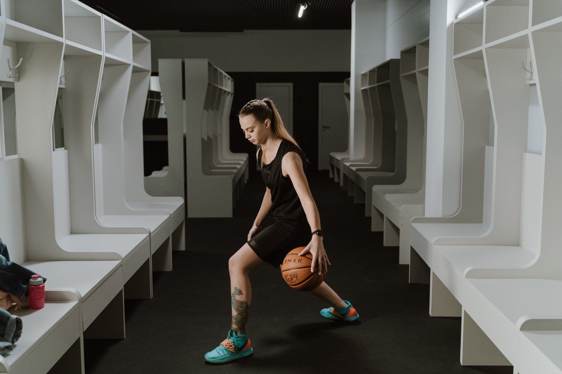 A woman is holding a basketball in a locker room.