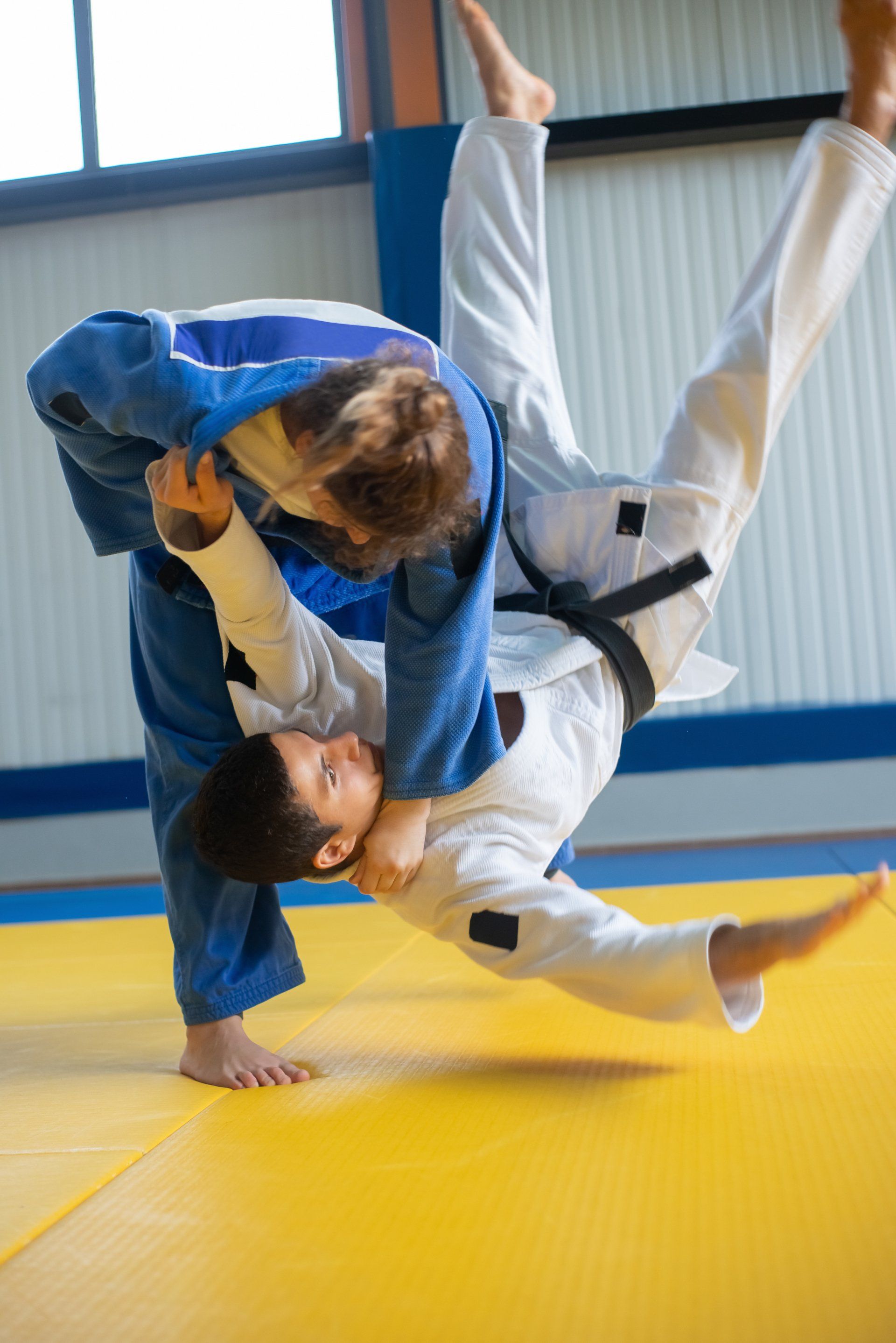 Een man en een vrouw beoefenen judo op een mat in een sportschool.