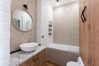 Modern bathroom with a white tile shower and wood accent wall.