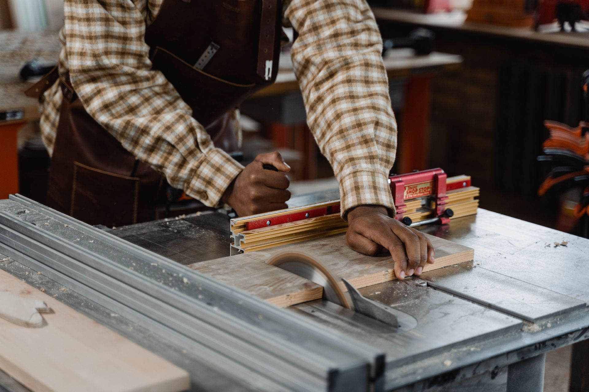 A man is cutting a piece of wood on a table saw.
