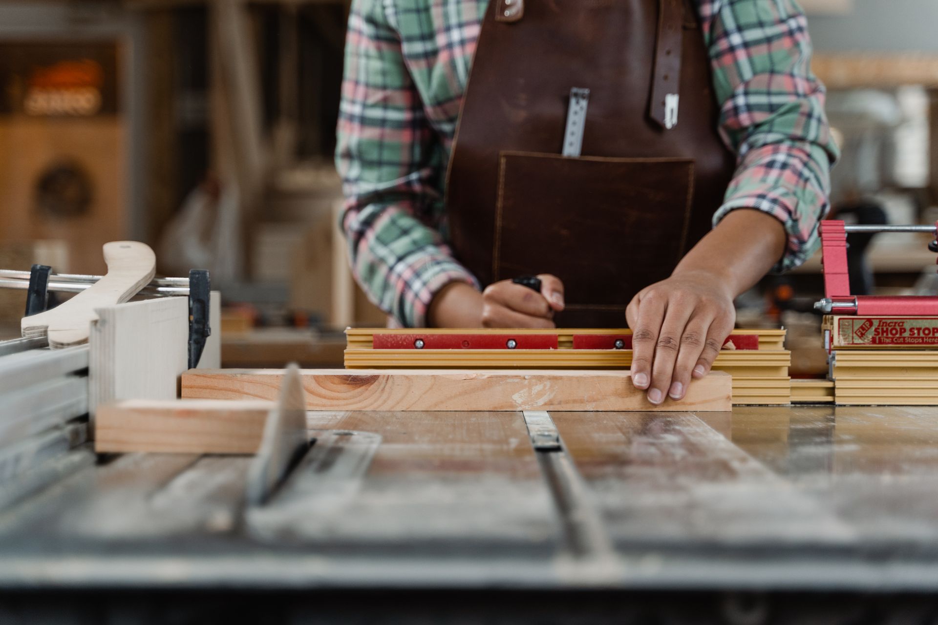 A man is measuring a piece of wood on a table saw.