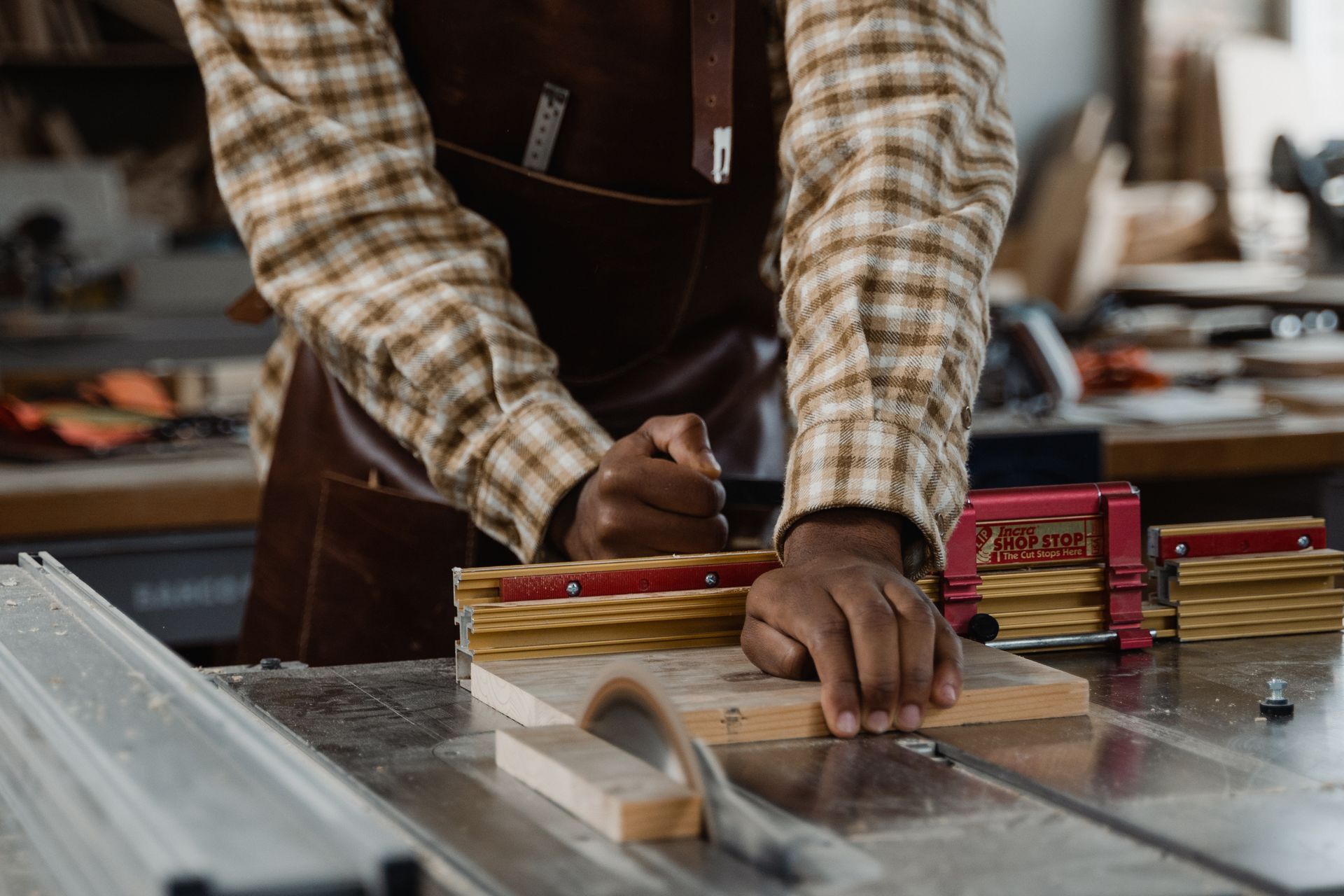 A man is cutting a piece of wood on a table saw.
