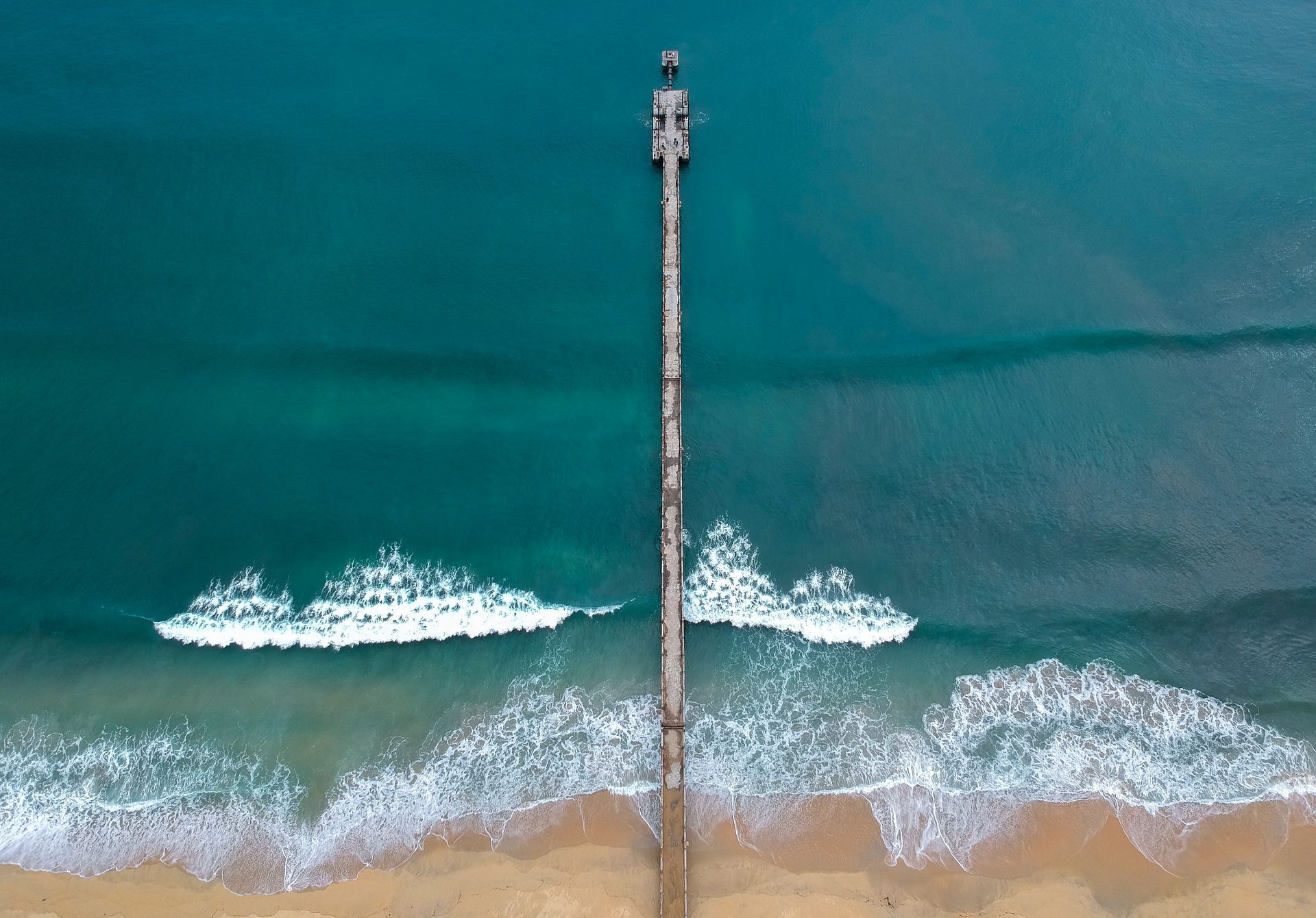 An aerial view of a pier in the middle of the ocean.