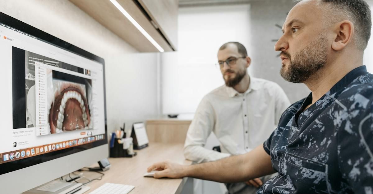 Two men are looking at a computer screen in a dental office.