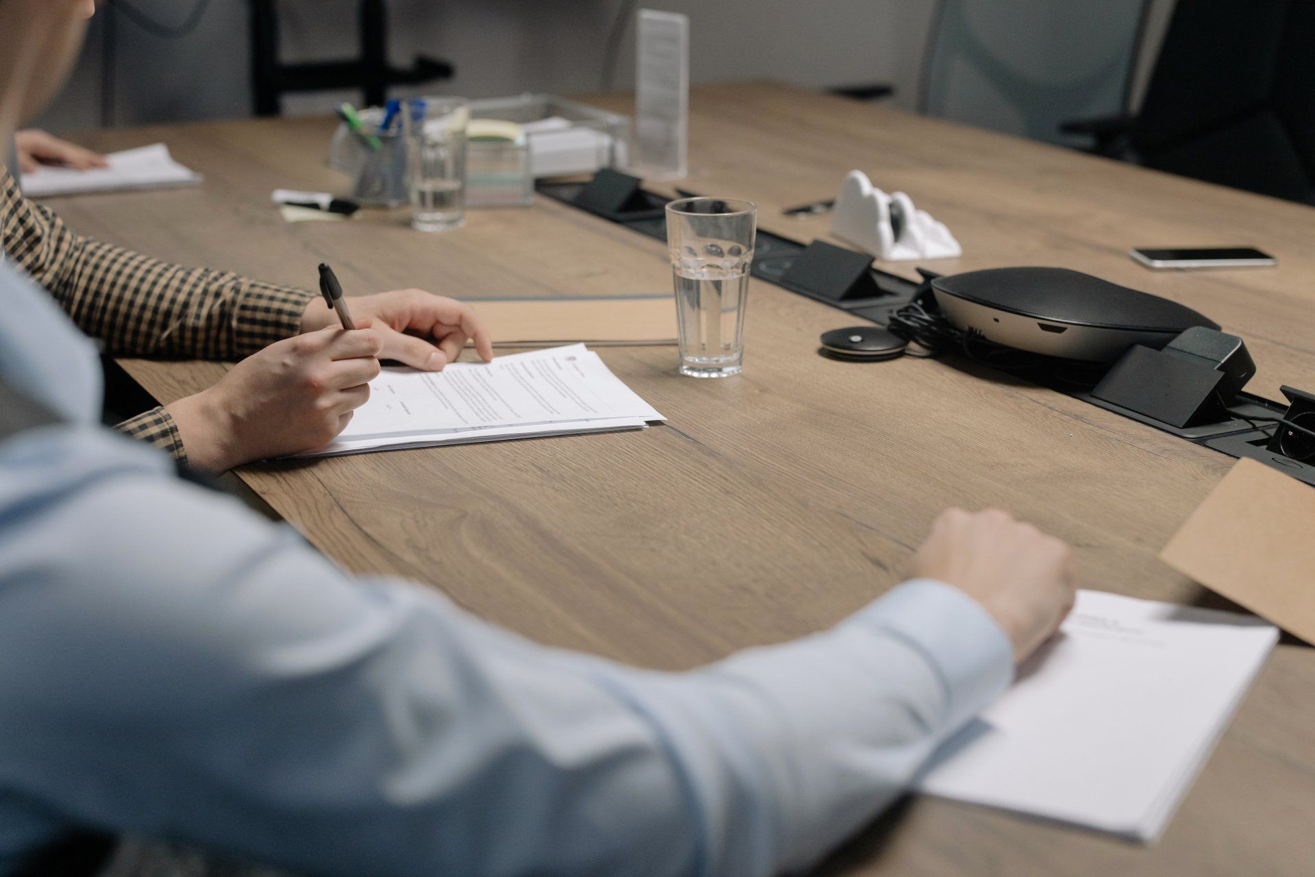 A man is sitting at a conference table writing on a piece of paper.