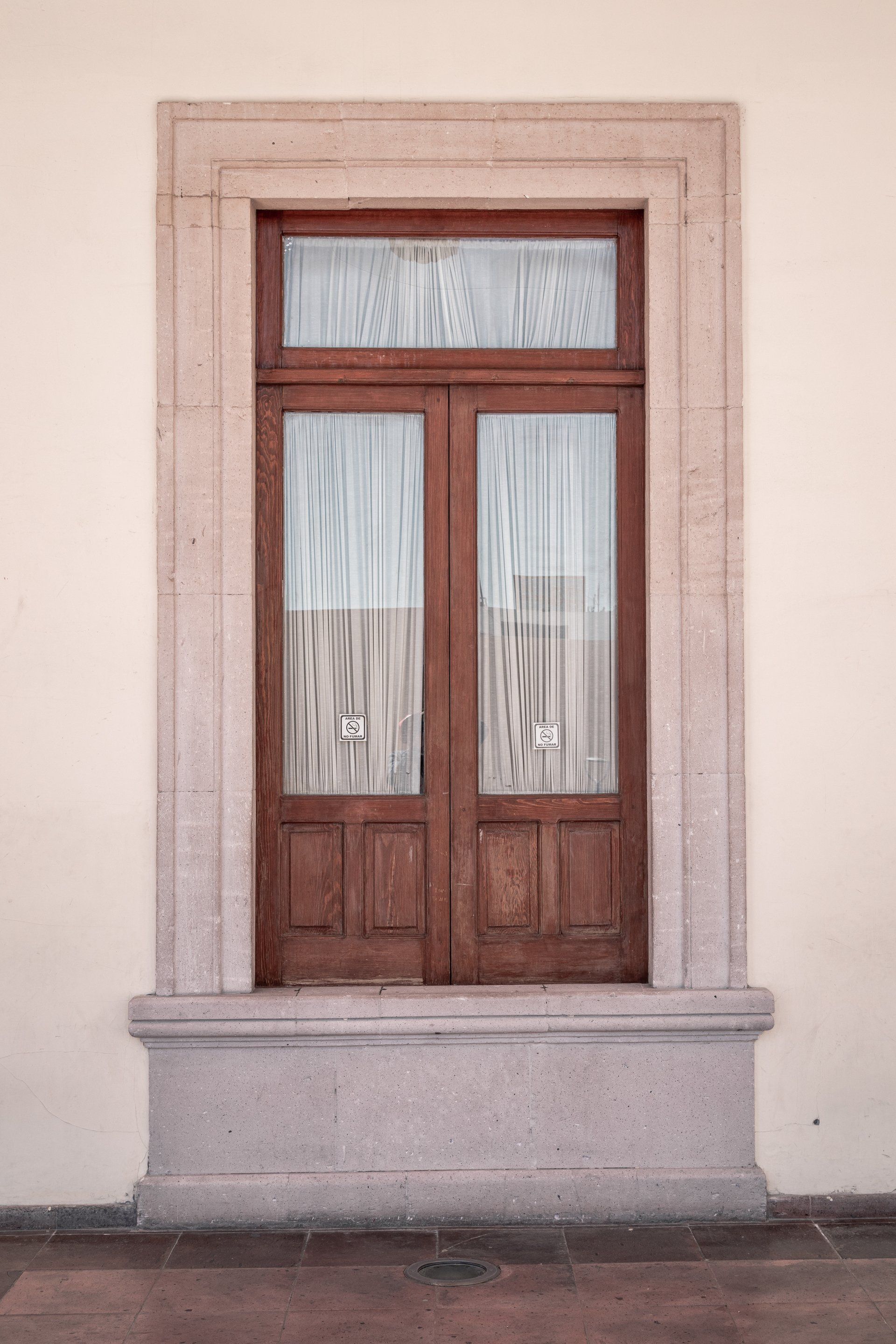 A wooden door with a stone frame is on a white wall.