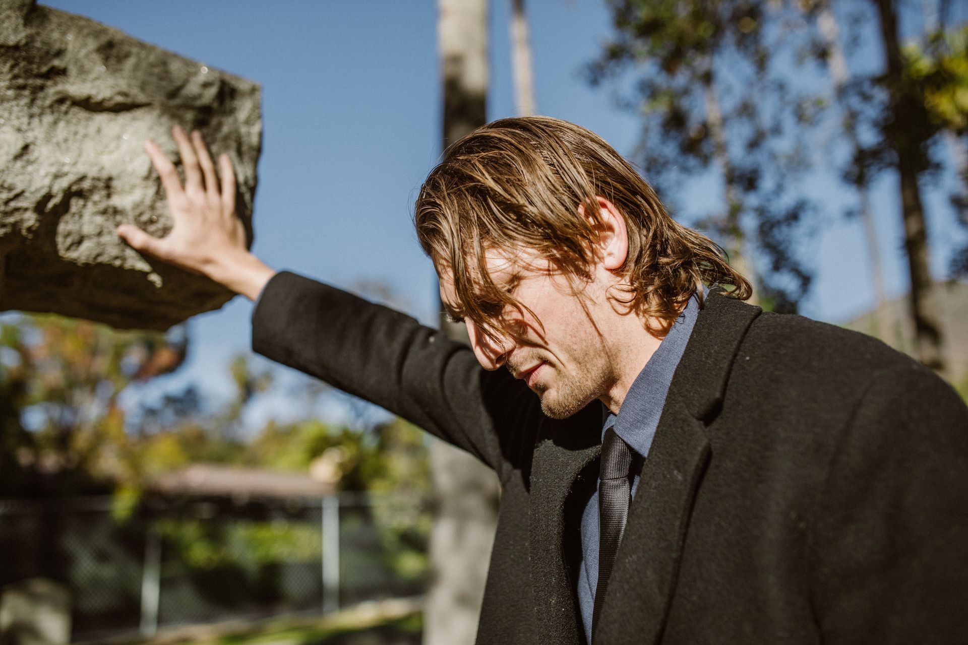 a man in a suit and tie is holding a large rock over his head .