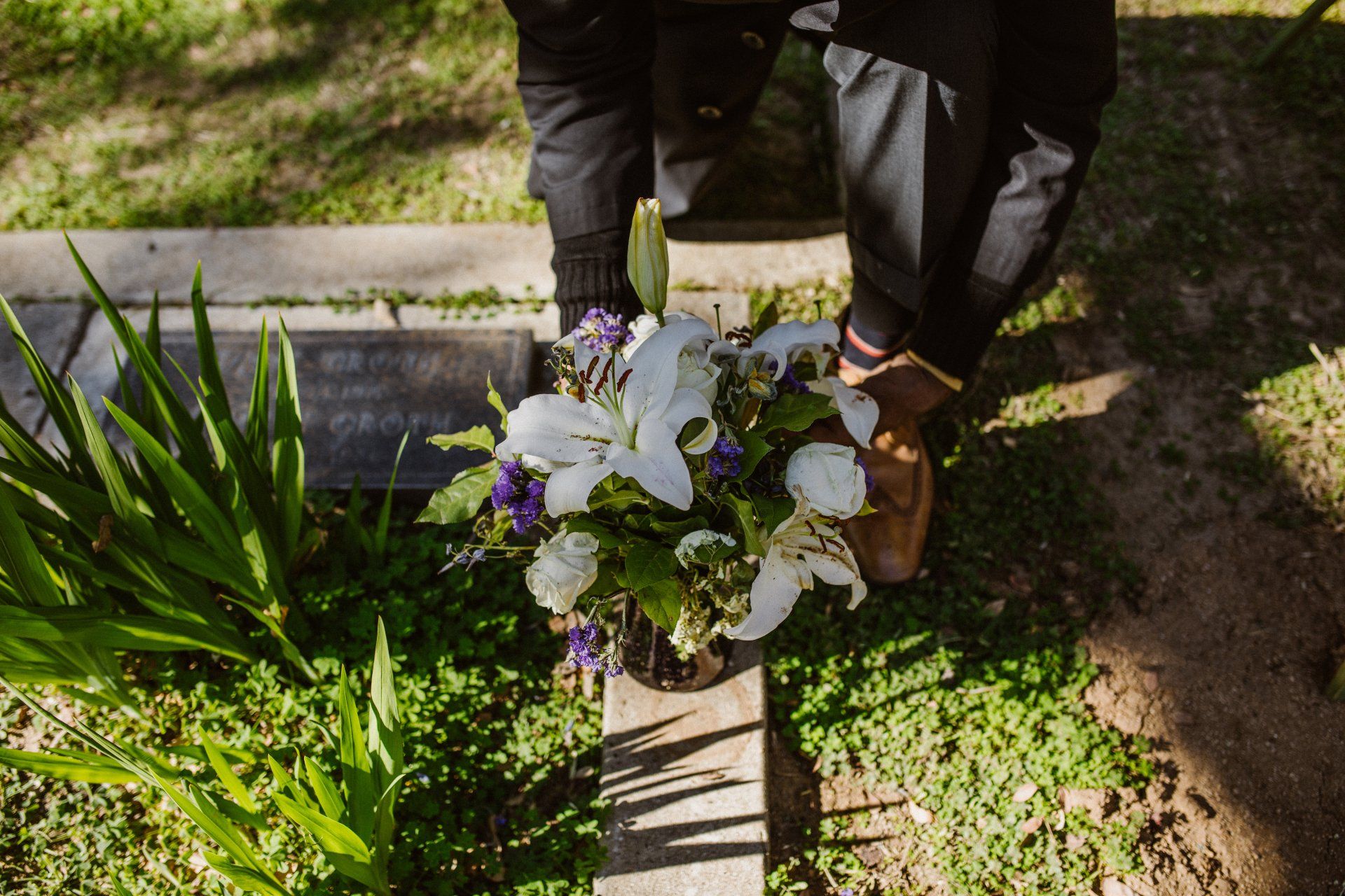 A person is putting flowers on a grave in a cemetery.