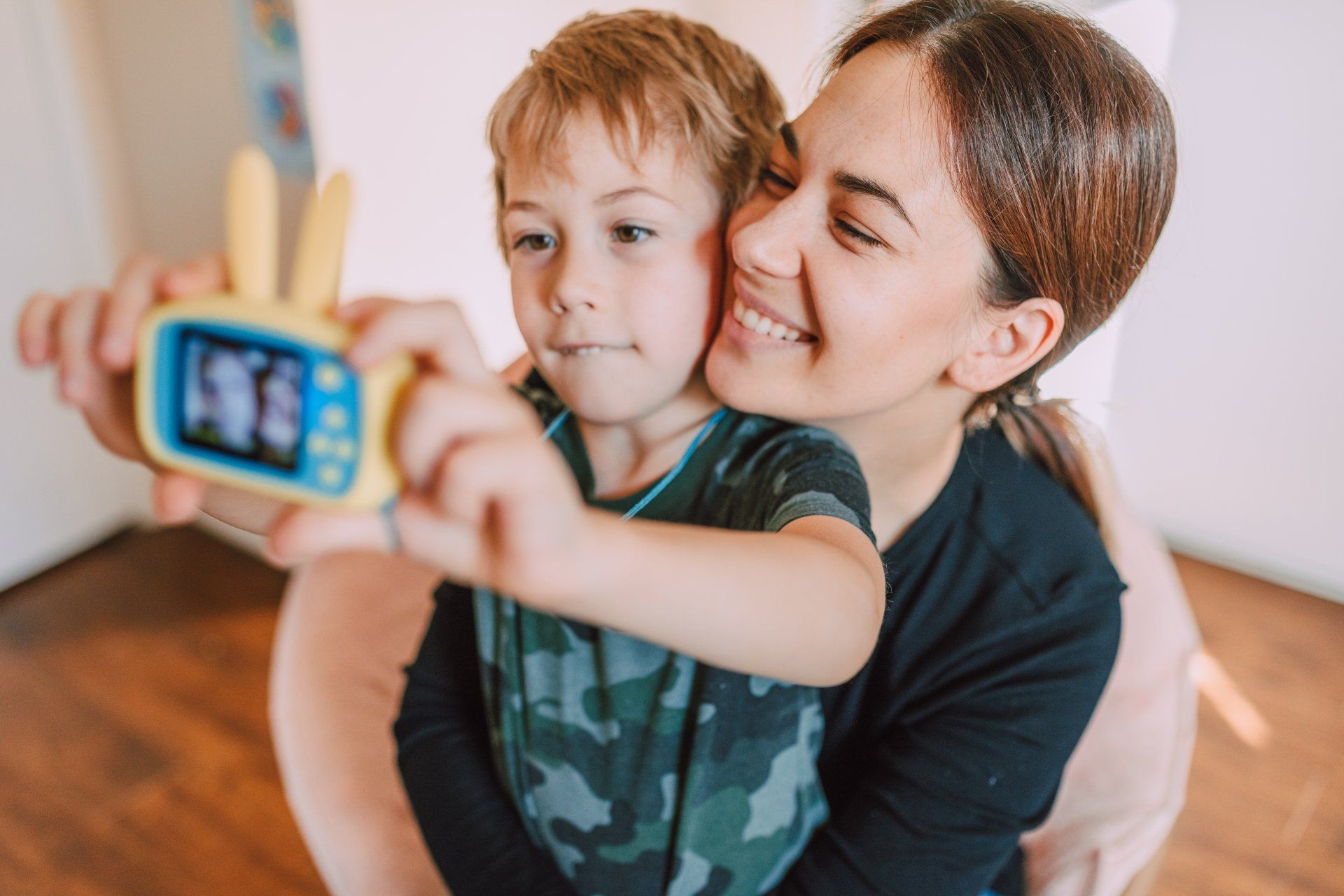 A woman is taking a picture of her son with a toy camera.
