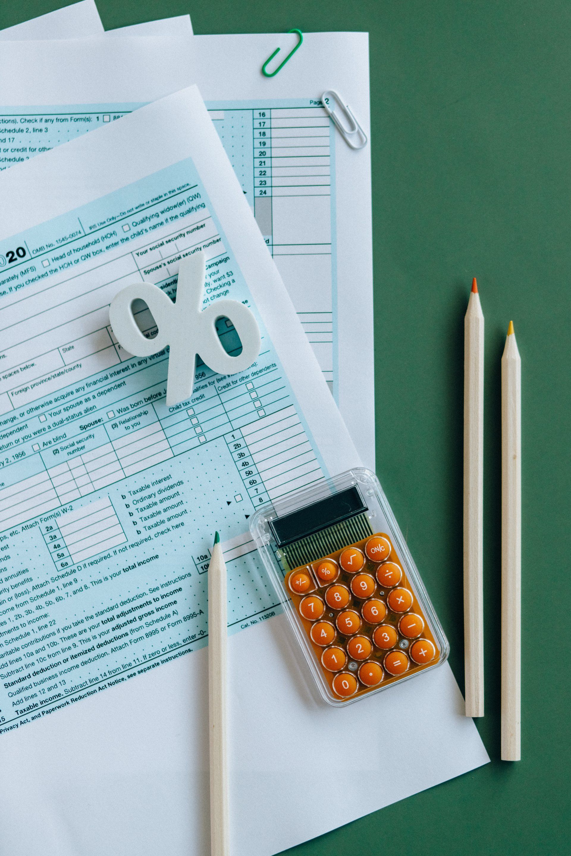 A calculator is sitting on top of a piece of paper next to pencils.