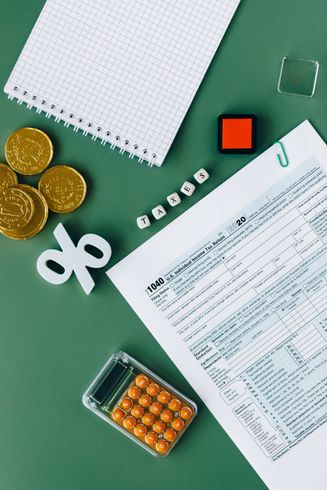 A calculator , coins , a notebook , and a tax form are on a green table.