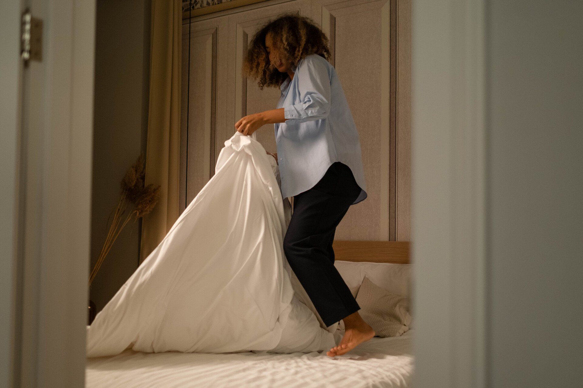 a woman folding her bed sheet