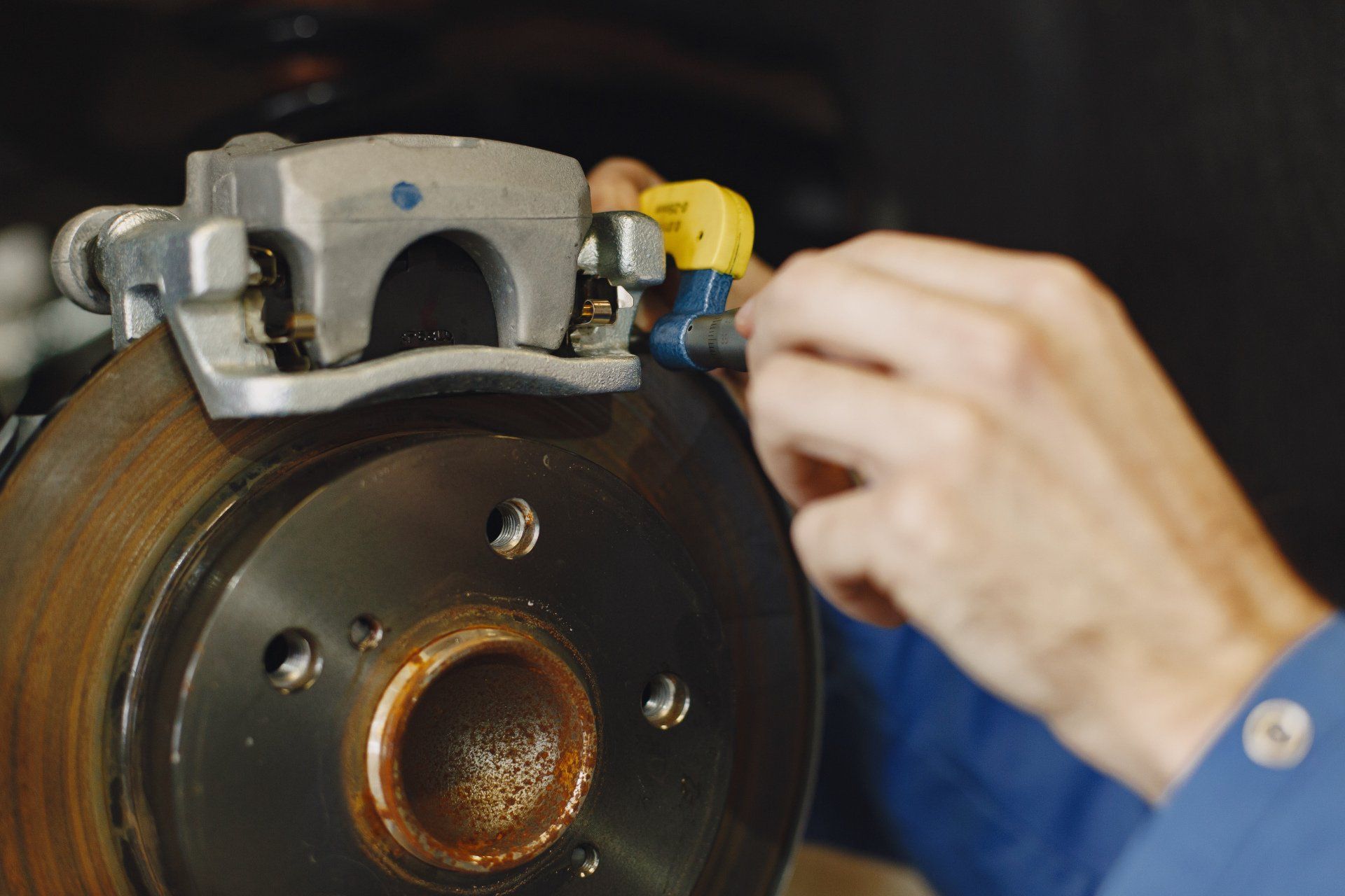 A person is working on a brake caliper on a car.