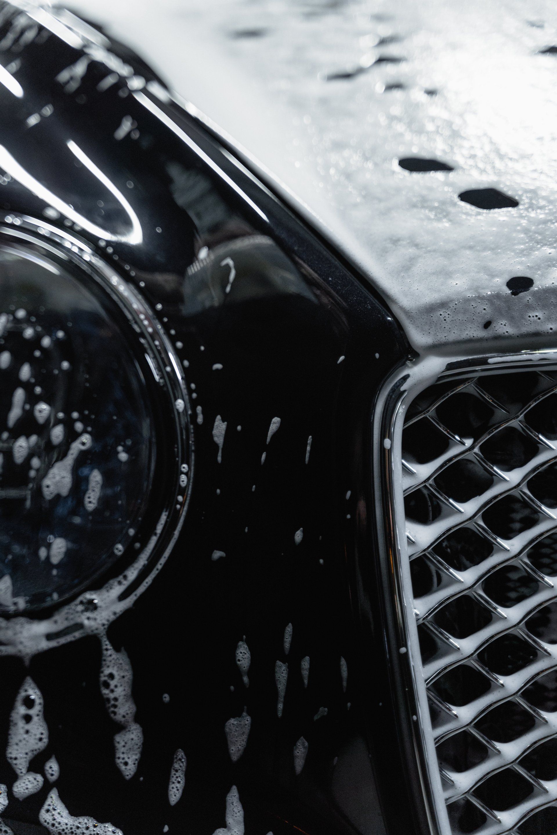 Ein schwarzes Auto wird mit Wasser und Seife gewaschen.