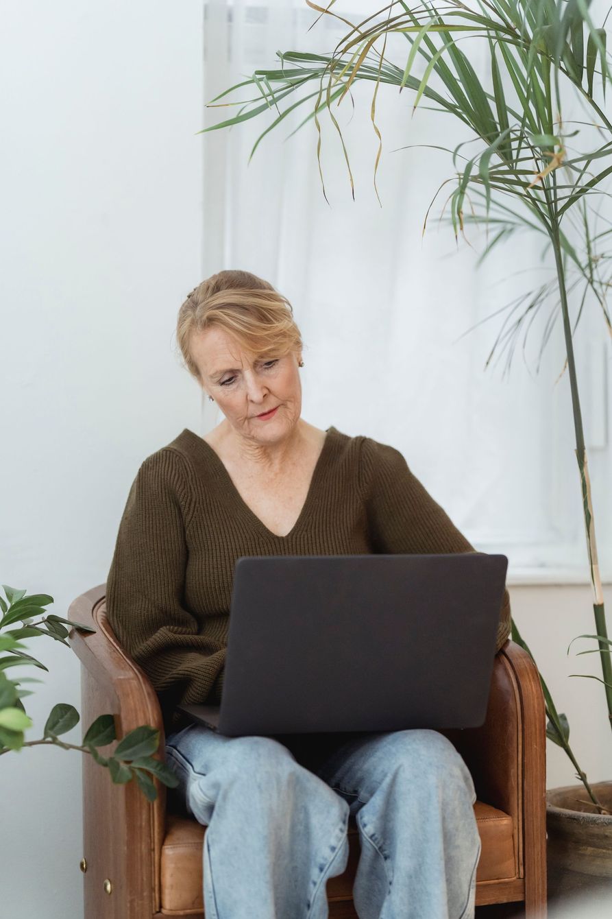 A woman is sitting in a chair using a laptop computer.