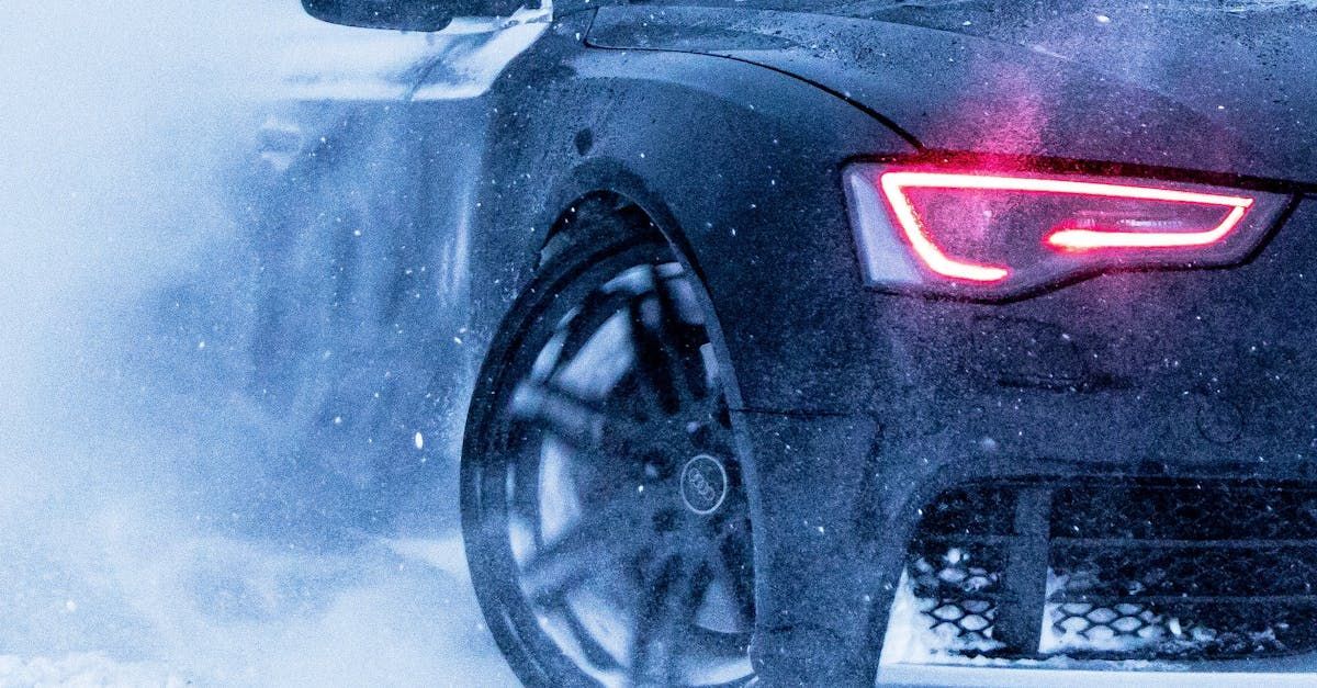 Photo of a black sedan with illuminated tail lights driving in snow