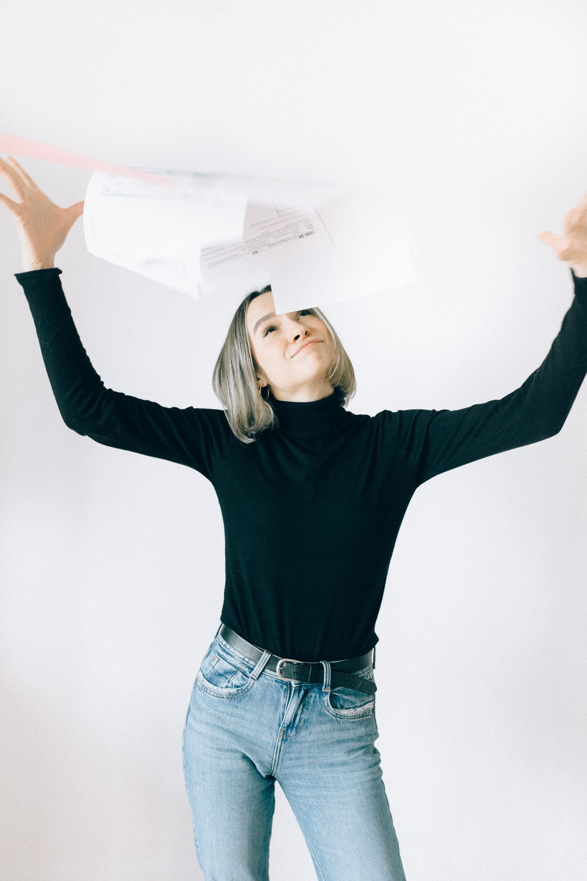 Woman with bob haircut and long blacksleeve shirt throwing 1040 papers in the air