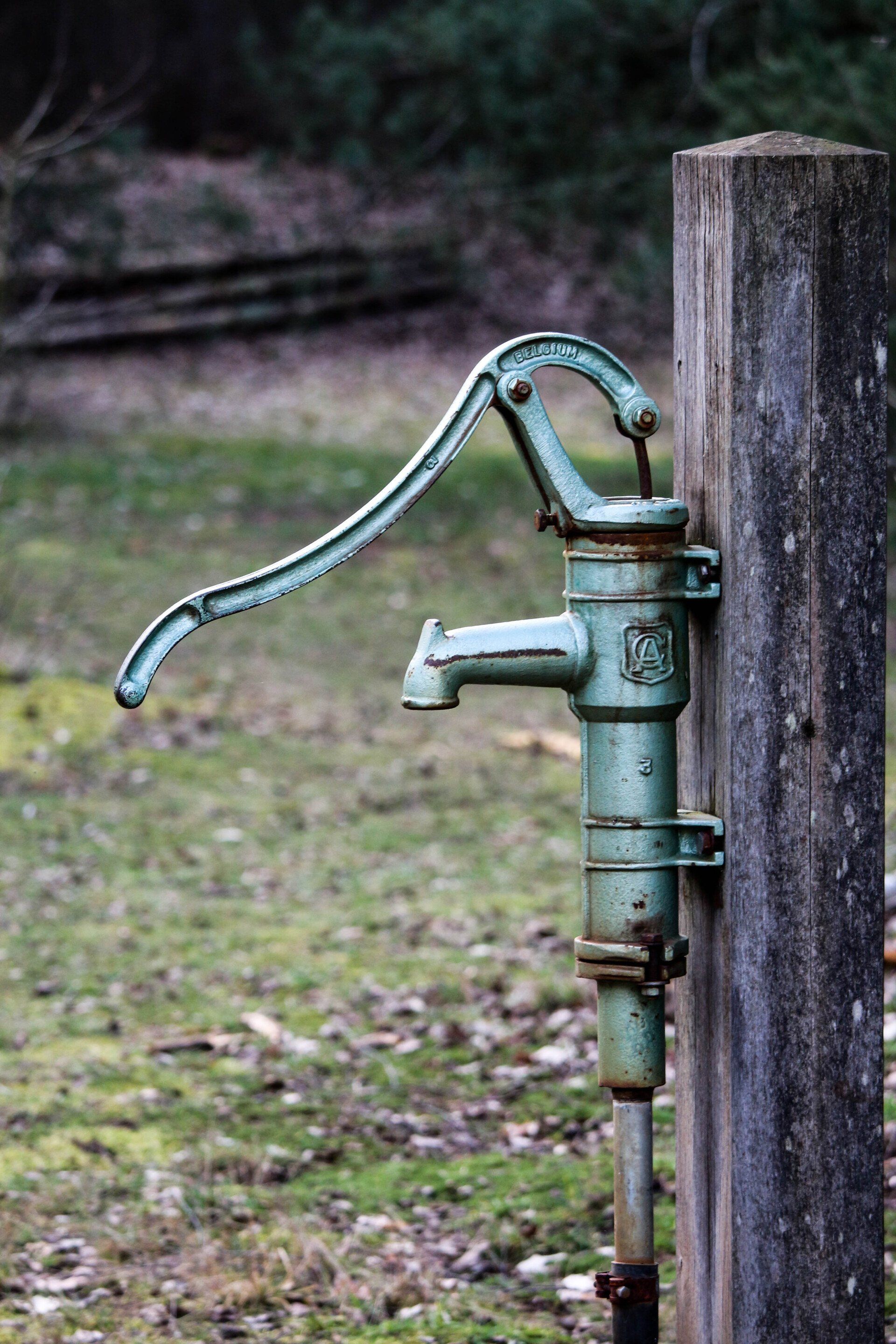an old water pump is attached to a wooden post