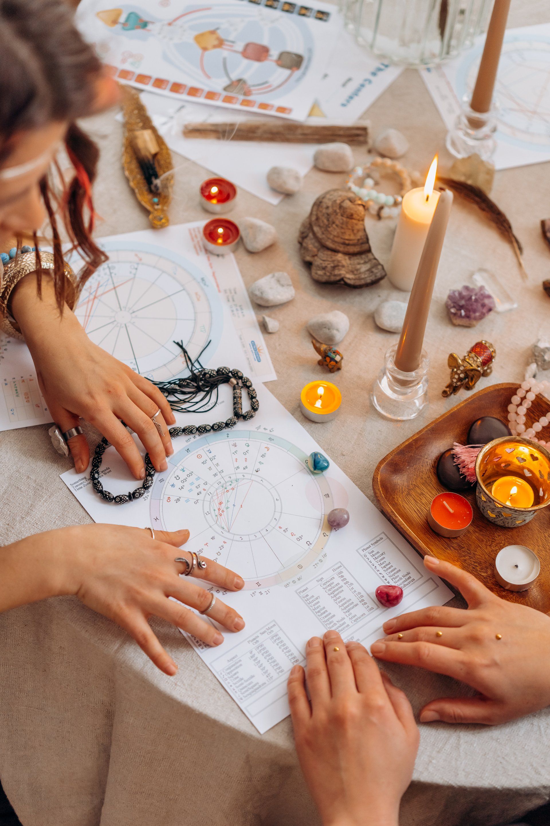 A couple of people are sitting at a table with candles and crystals.