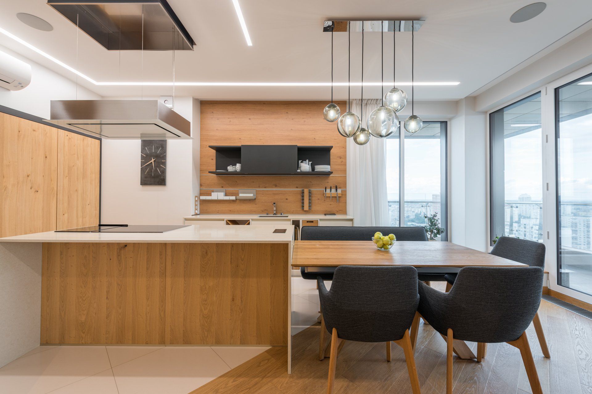 Cuisine moderne avec armoires en bois, îlot et table à manger avec chaises; espace lumineux.