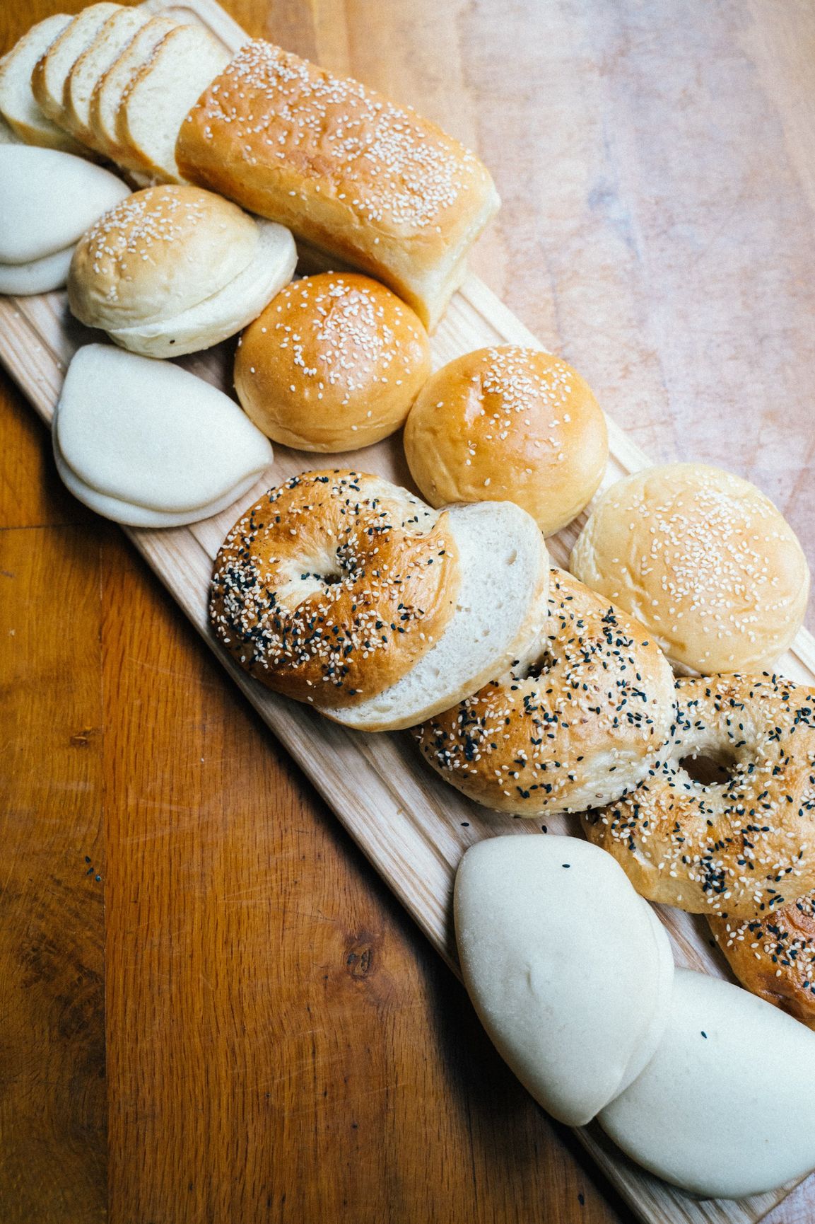 There are many different types of bread on the cutting board.