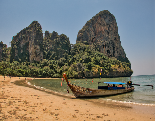 A boat on the beach with a mountain in the background