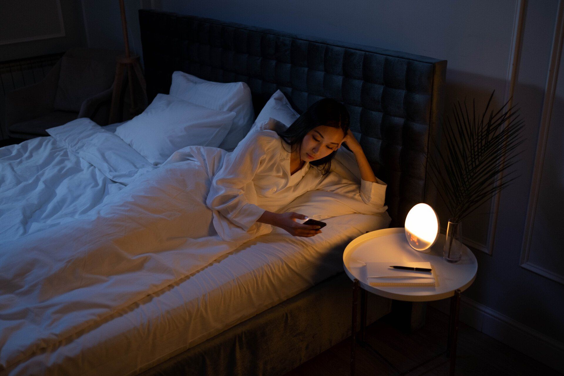 a woman is lying in bed looking at her phone