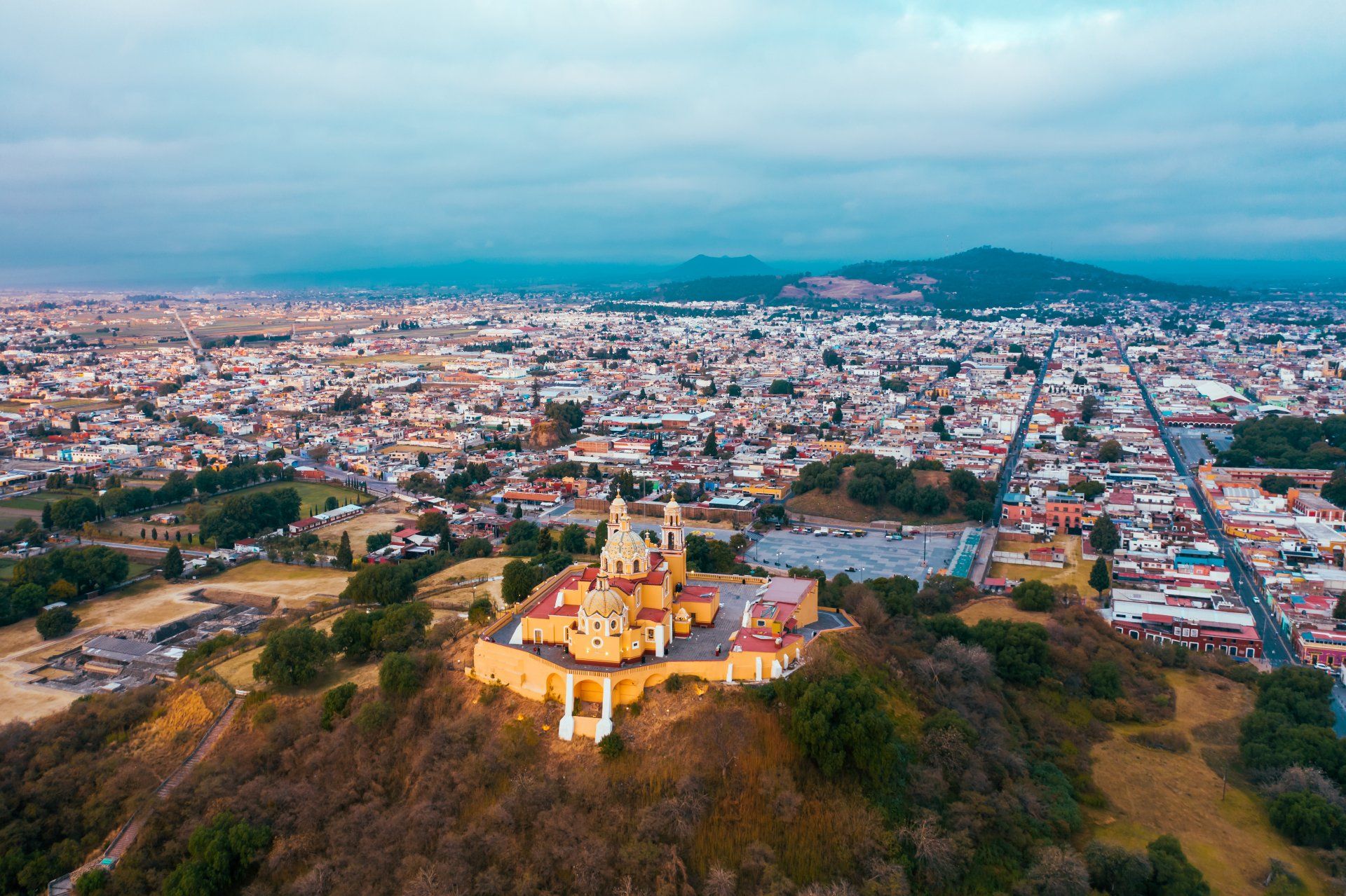 an aerial view of a church on top of a hill with a city in the background .