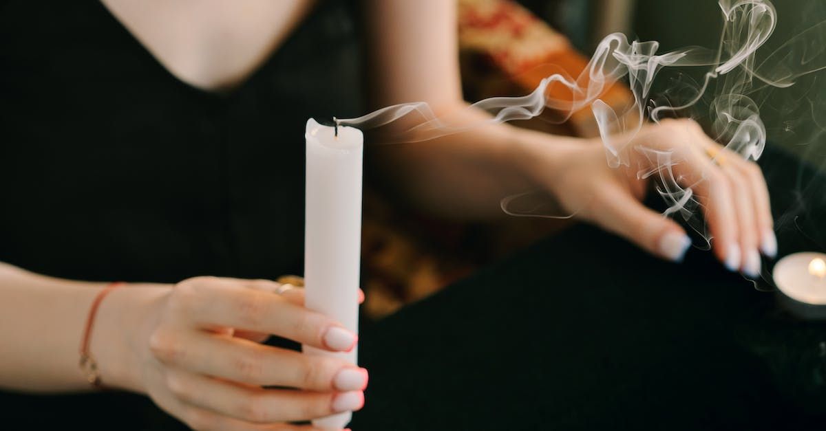 A woman is holding a white candle with smoke coming out of it.