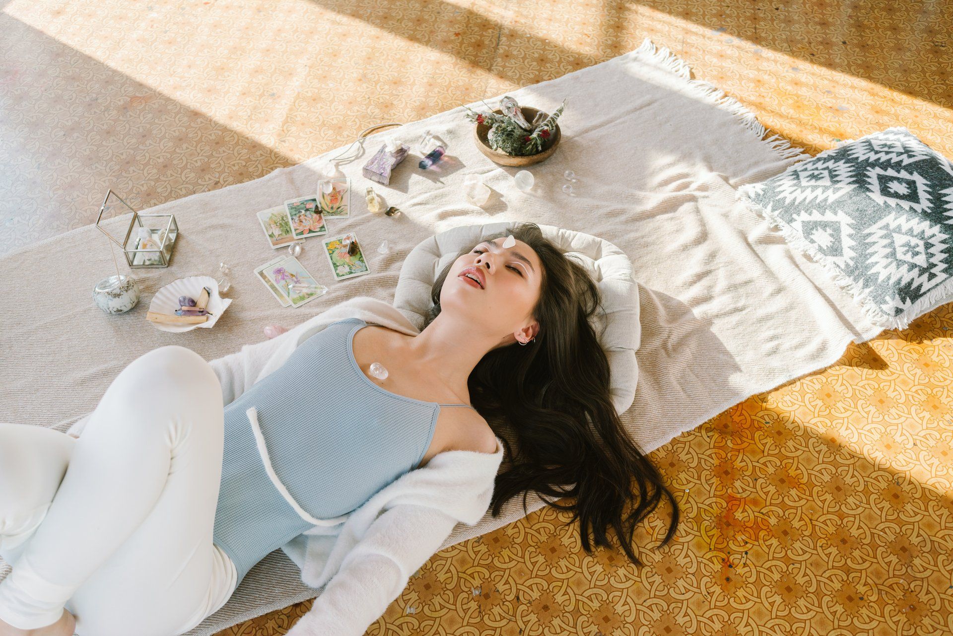 A woman is laying on a blanket on the floor.