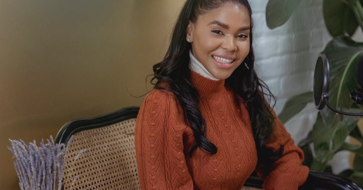 a woman in an orange sweater is sitting on a chair and smiling .