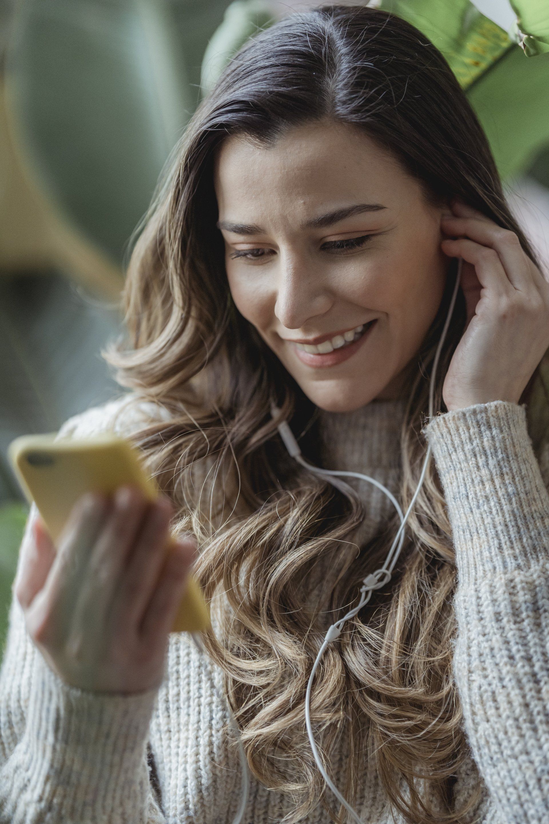 Une femme écoute de la musique sur son téléphone tout en portant des écouteurs.