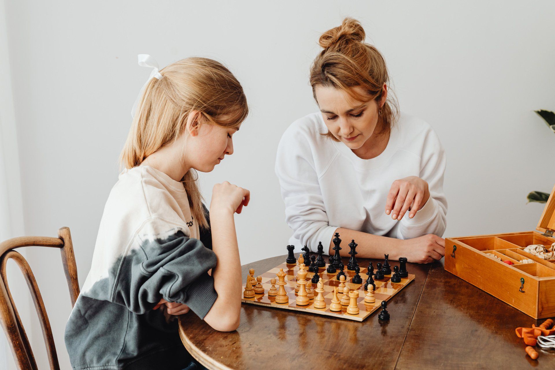 An image of a female adult with a female teenager playing a game of chess