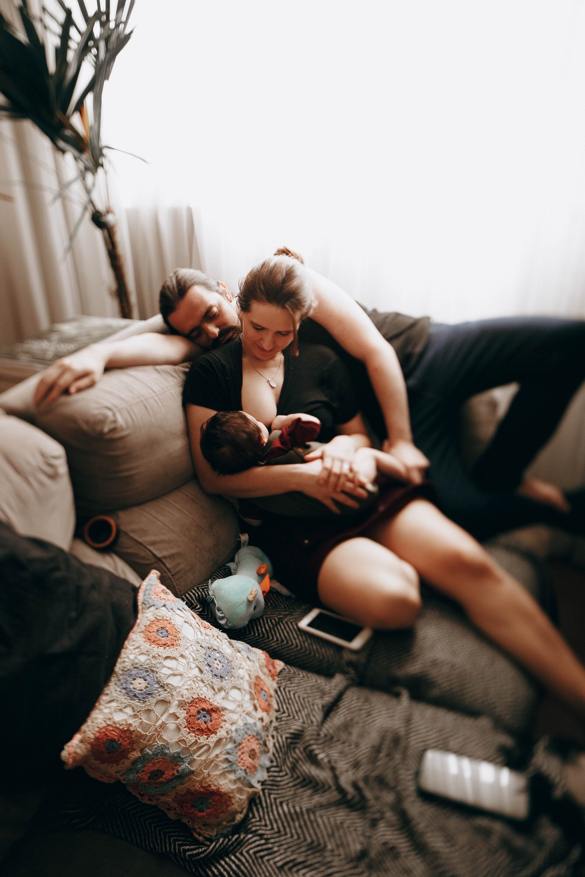 Mom and Dad on couch as mom breastfeeds newborn