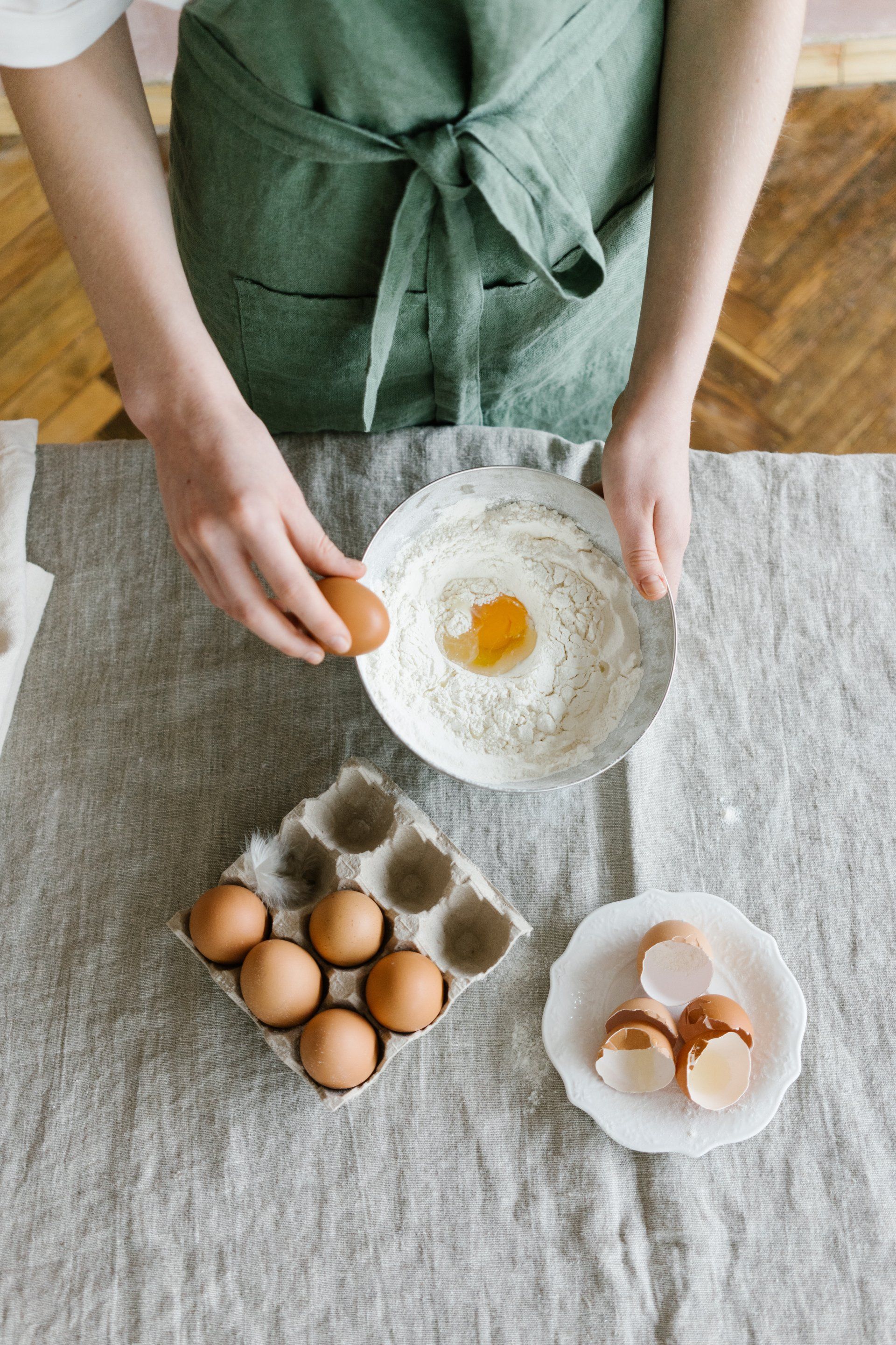 A person is cracking an egg into a bowl of flour.