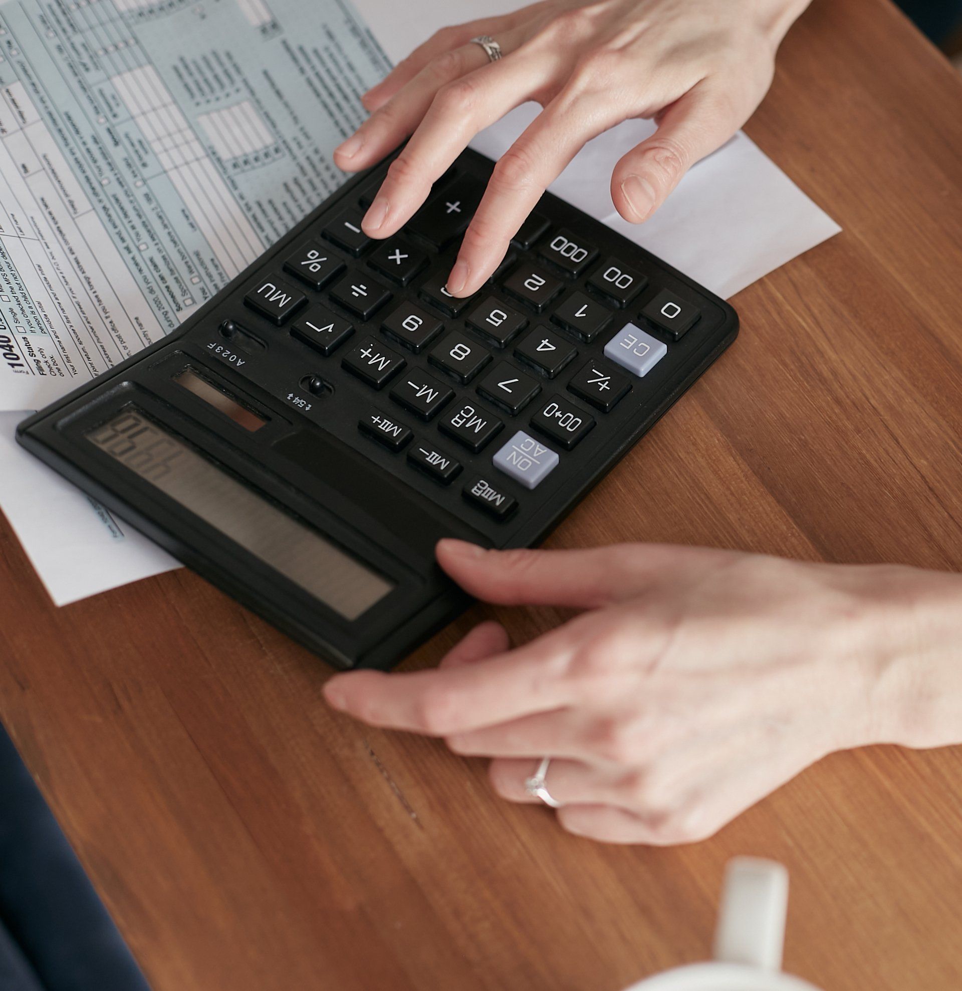 A person is using a calculator with the numbers 0-9 on it
