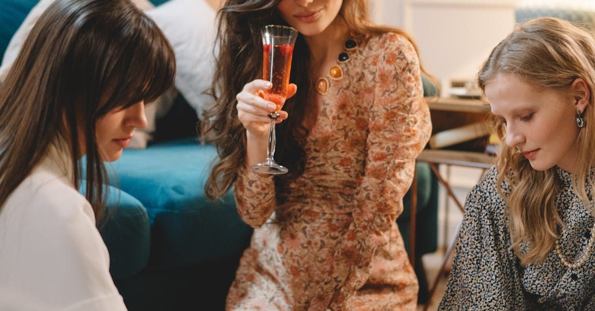 A group of women are sitting on the floor drinking wine.