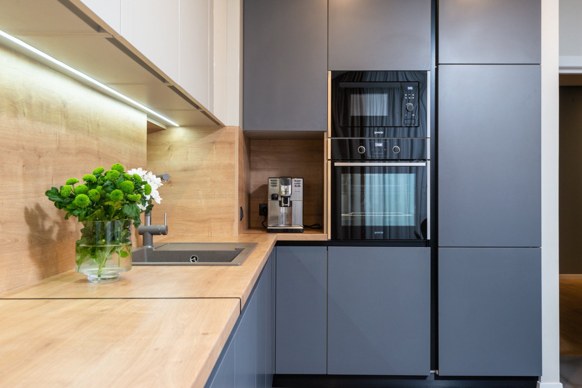 A kitchen with a sink , oven , microwave and a vase of flowers on the counter.