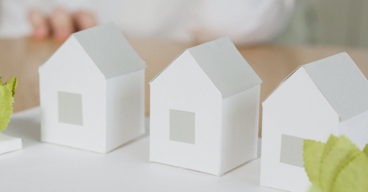 Three white paper houses are lined up on a table.